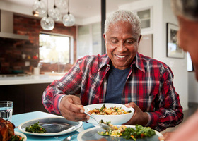 Older man eating fruit and vegetables at a table.jpg