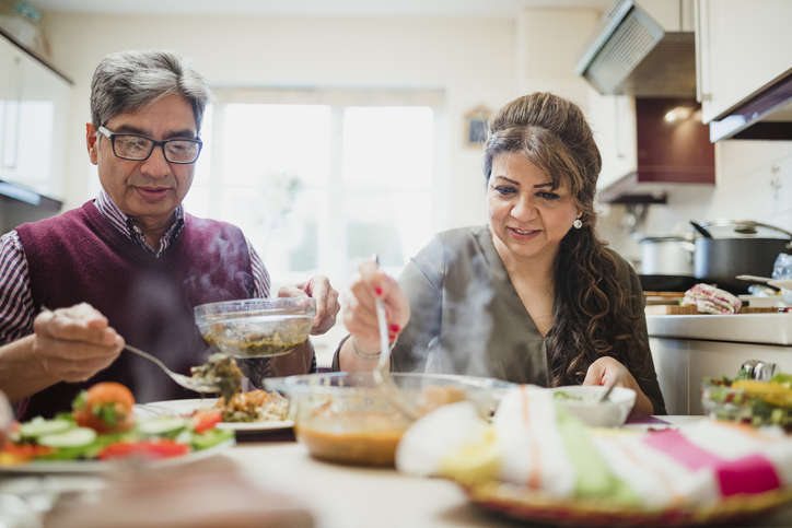 Mature couple are enjoying a homemade curry with salad at home.